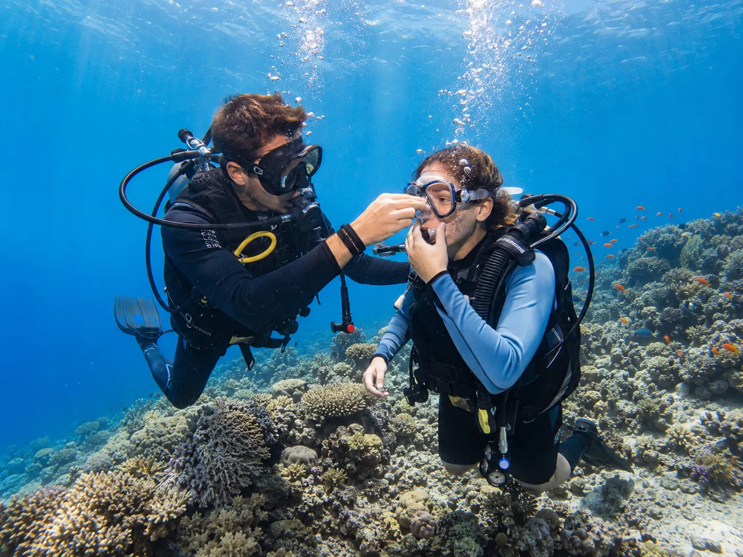 First-time diver breathing underwater with an instructor in shallow Red Sea water, Hurghada